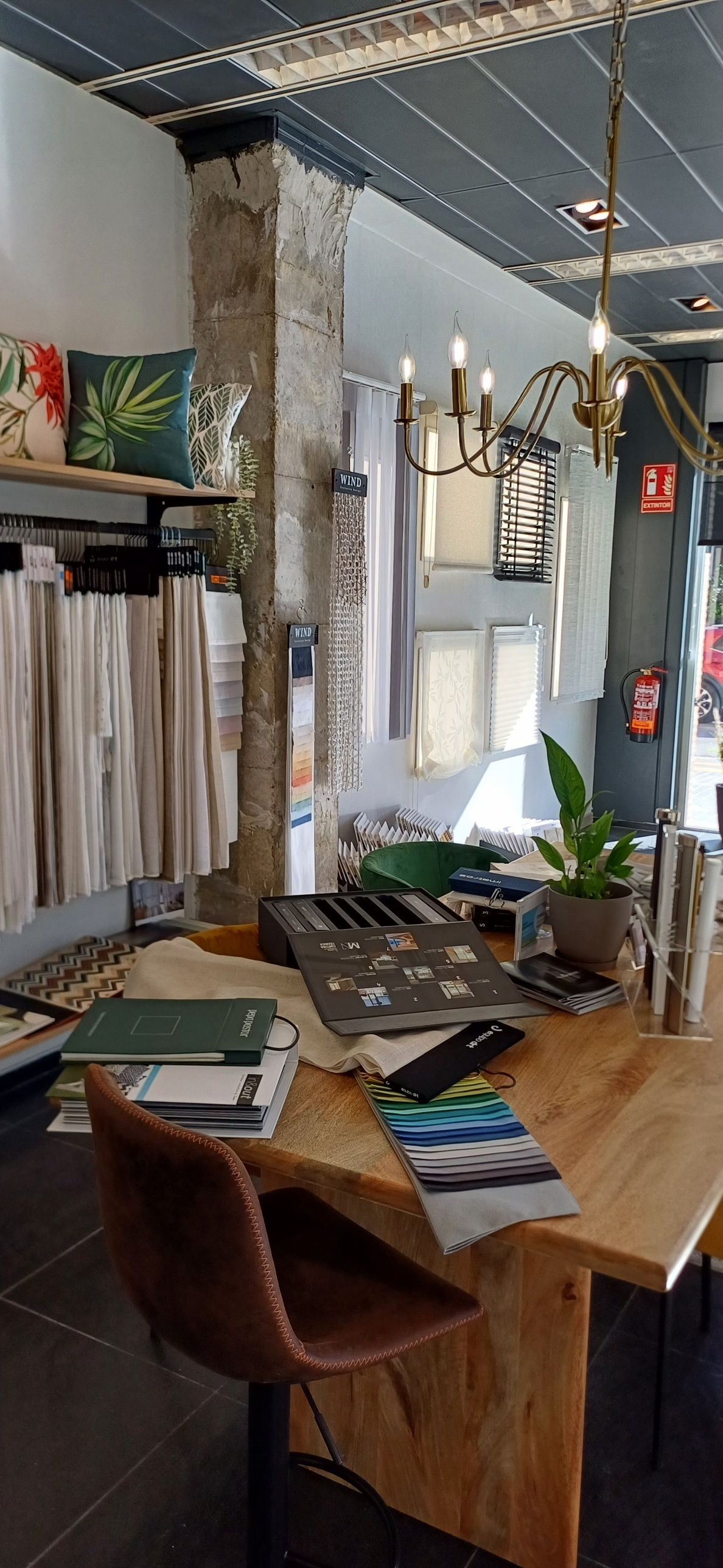 Mesa del estudio con muestrarios de telas, catálogos y una lámpara dorada