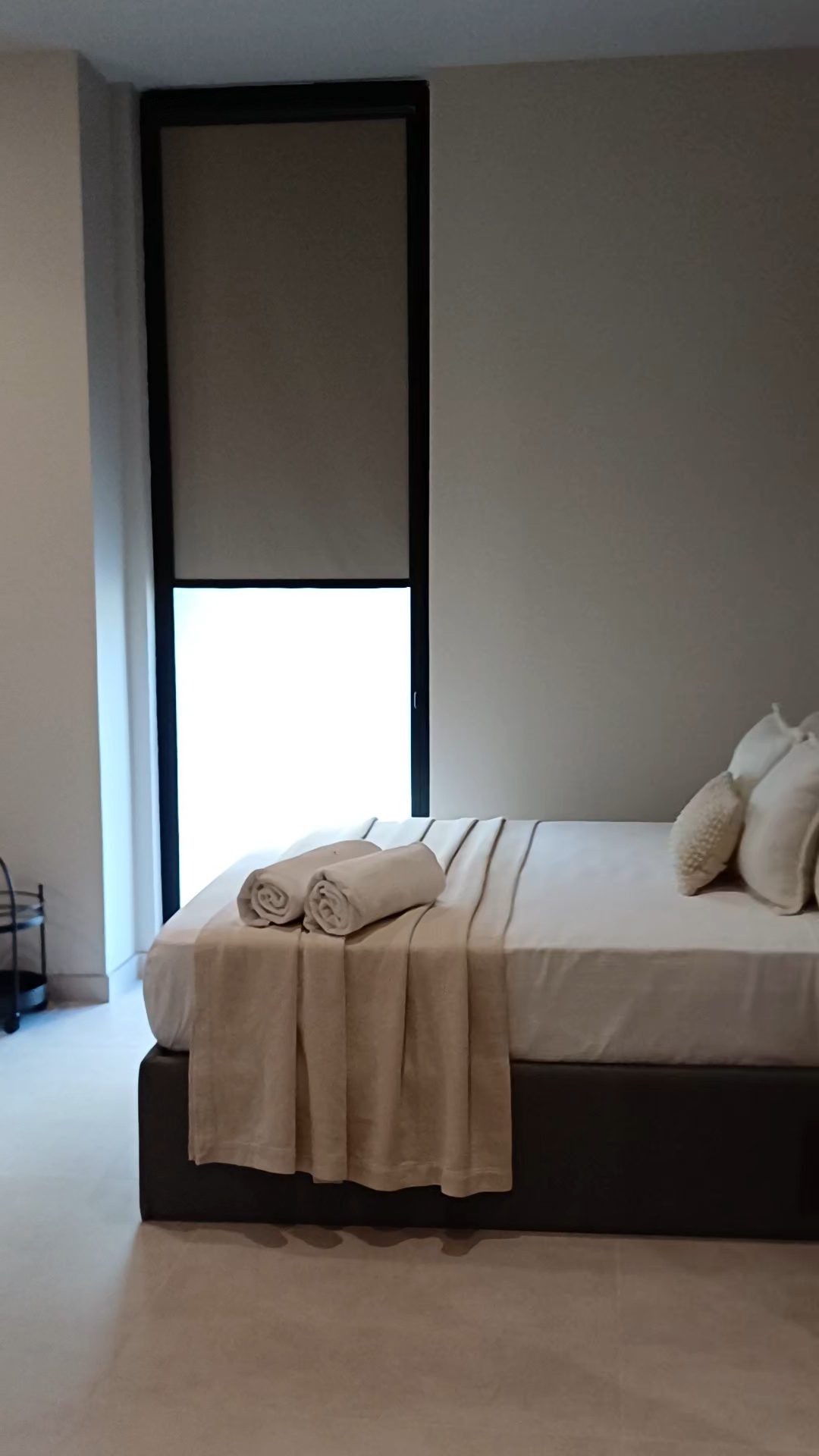 Dormitorio de apartamento con enrollable en una ventana alta con marco negro
