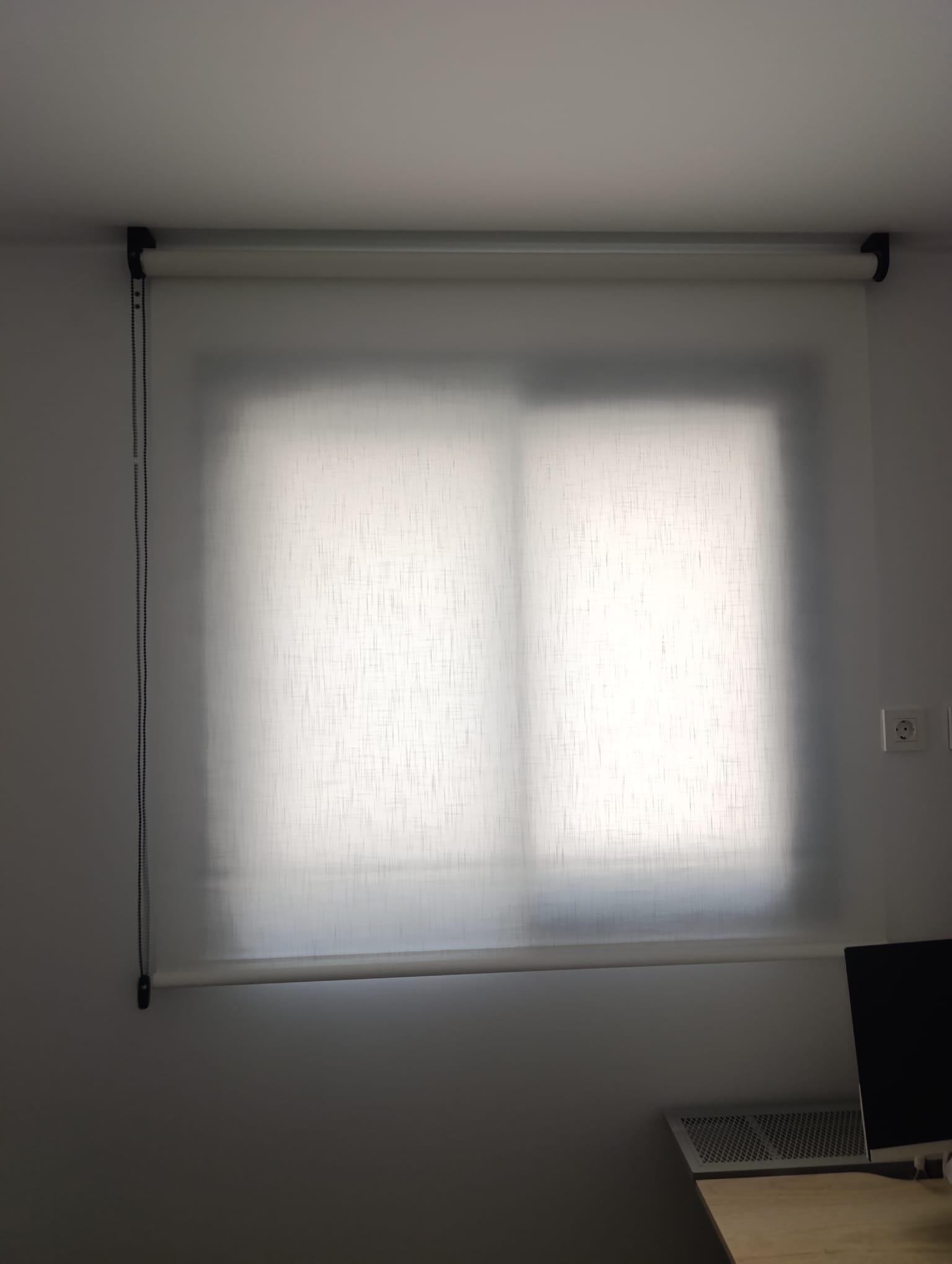 Enrollable de lino blanco en la ventana de un dormitorio