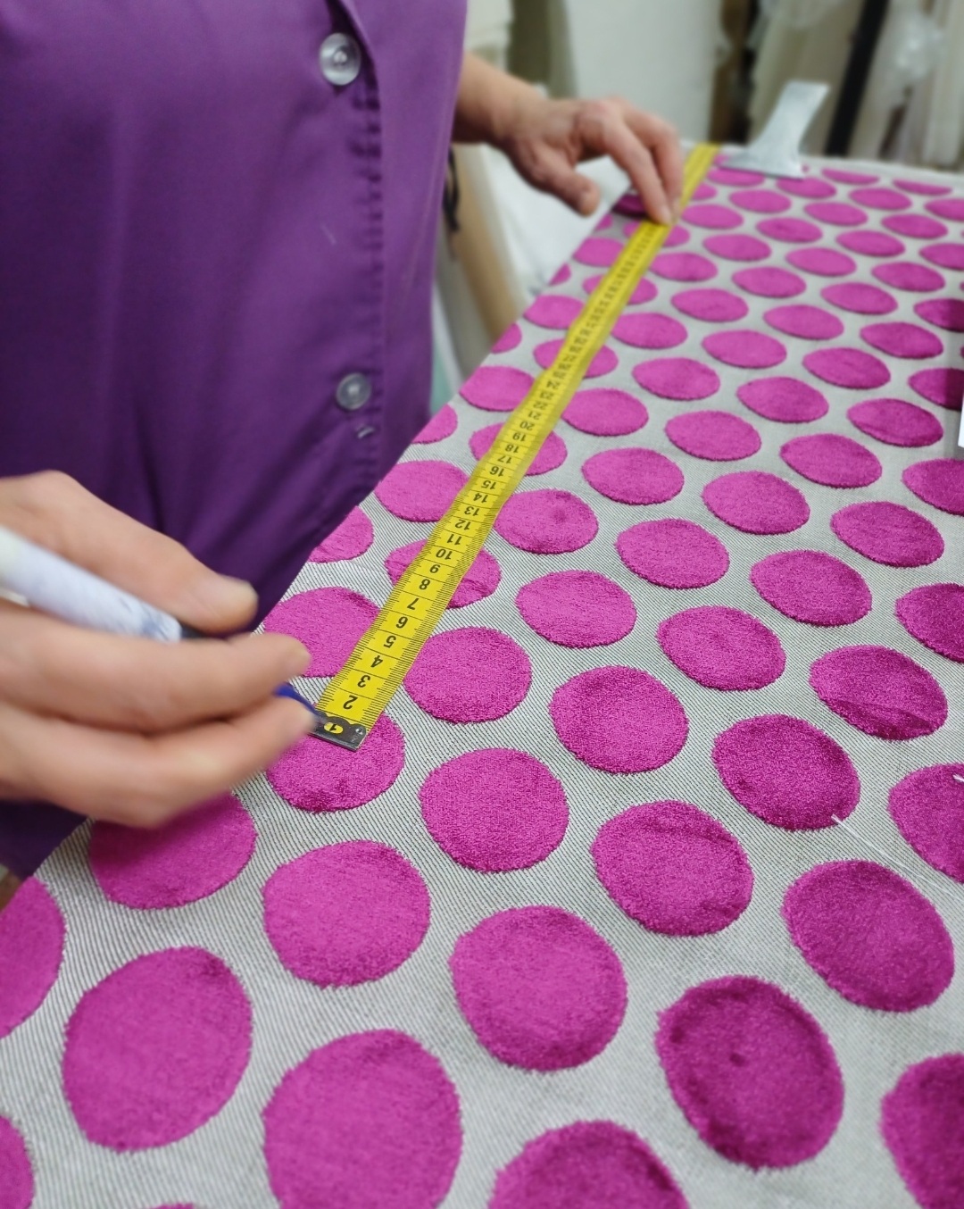 Medición de una tela de terciopelo fucsia con topos usando una cinta métrica
